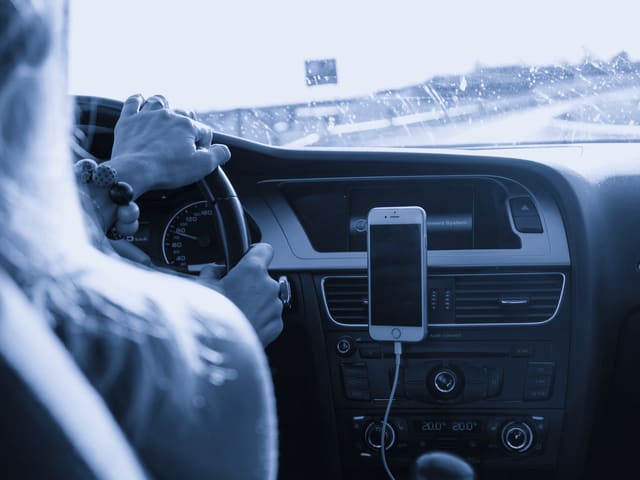 Pessoa ao volante de um carro, vista de dentro do veículo